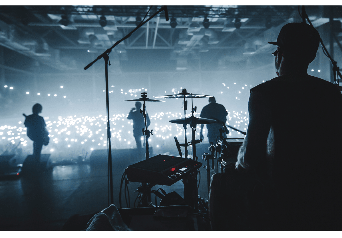 A man is playing drums in a darkened auditorium, surrounded by other musicians. AI generated content